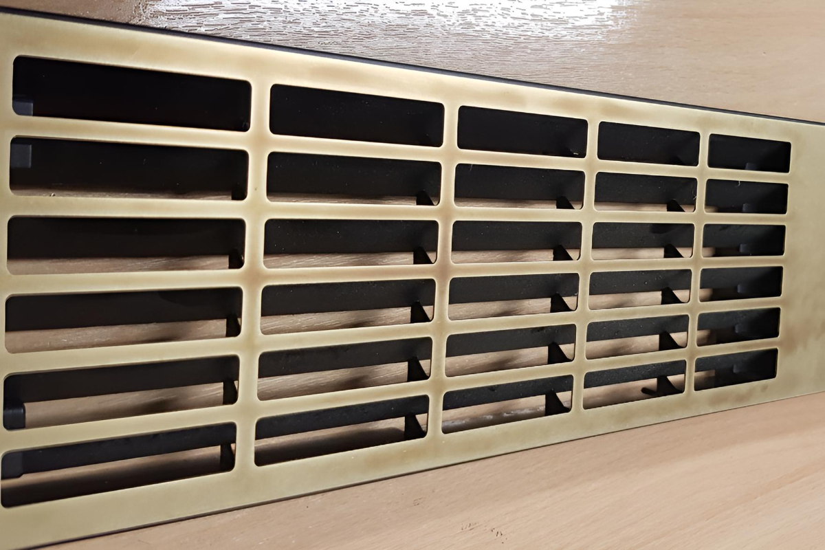 Aged brass sheet with rectangular perforations used as a decorative vent grille