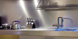 Brushed stainless steel worktop with integrated sink and full-height splashback in a contemporary kitchen, fabricated by Metal Sheets Ltd.