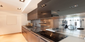 Brushed stainless steel splashback with integrated utensil rail and matching worktop in a modern fitted kitchen, fabricated by Metal Sheets Ltd.