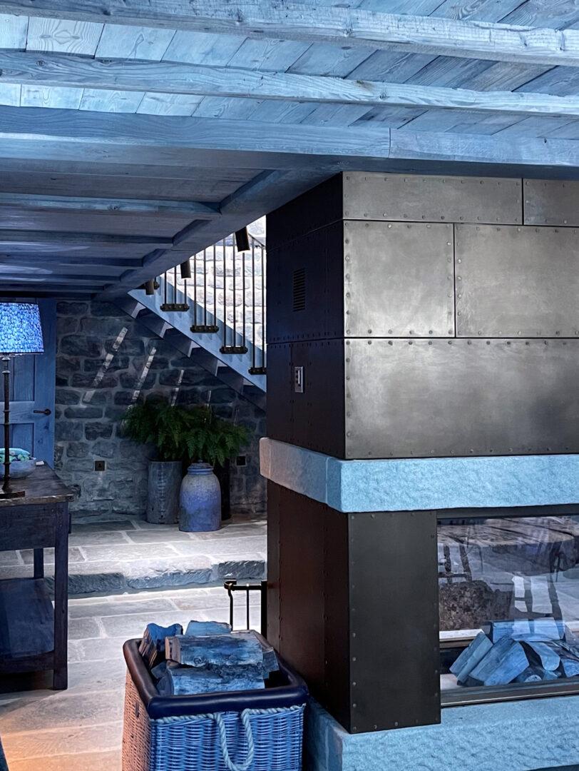 Blackened corten steel sheet panels installed around a fireplace as architectural wall cladding.