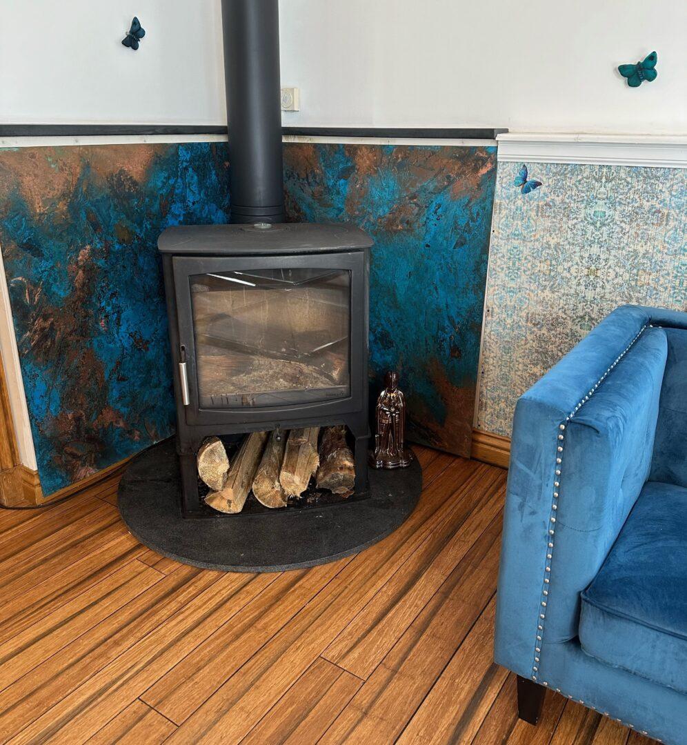 Blue patina copper wall panel installed as a decorative heat shield behind a wood burning stove.