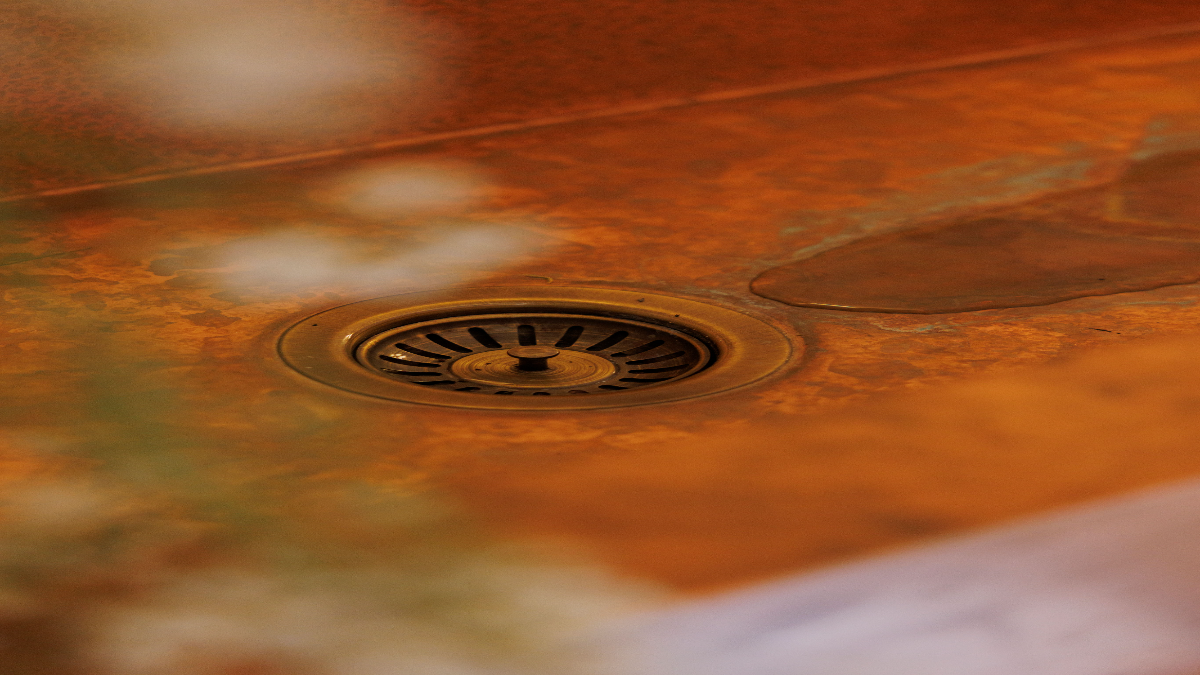 Copper trough sink drain surrounded by the naturally aged and developing copper patina