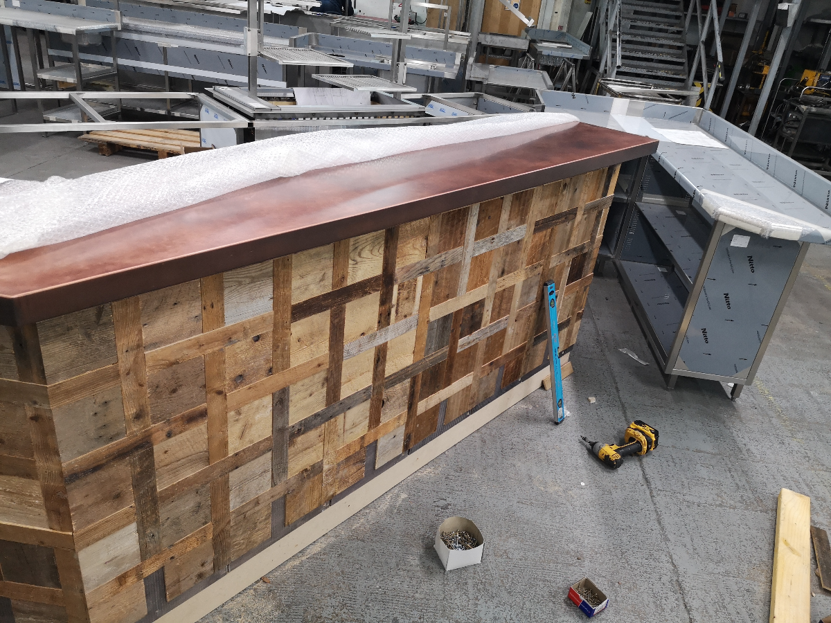 Bespoke copper bar top being fitted to timber base at ScoMac workshop